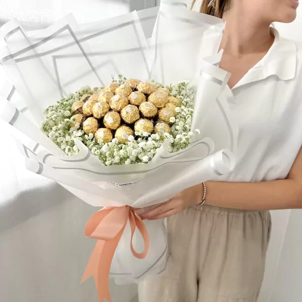 Bouquet of 19 Ferrero Rocher chocolates surrounded by white gypsophila, tied with a peach ribbon.