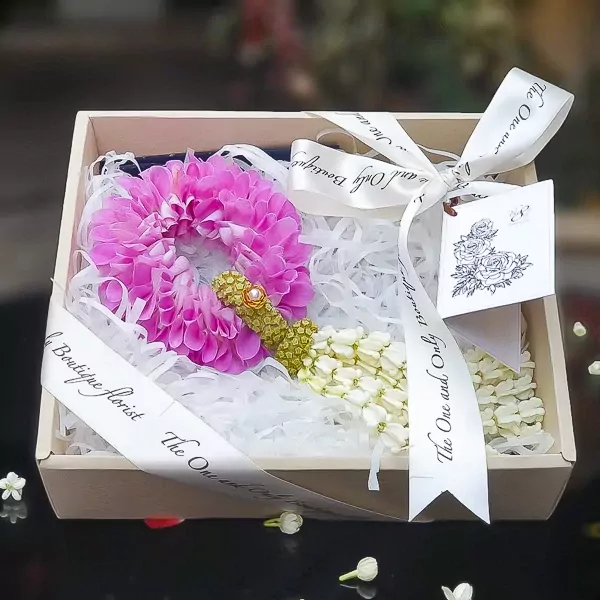 Gift box with pink mum lei, jasmine lei, and decorative ribbon.