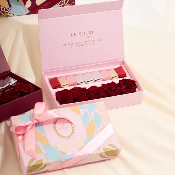 Pink gift box with preserved red roses and chocolates, and another pink box with a ribbon.