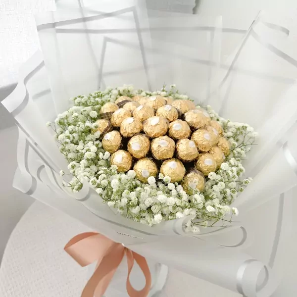 Bouquet of 19 gold-wrapped Ferrero Rocher chocolates surrounded by white baby's breath flowers and sheer white wrapping.