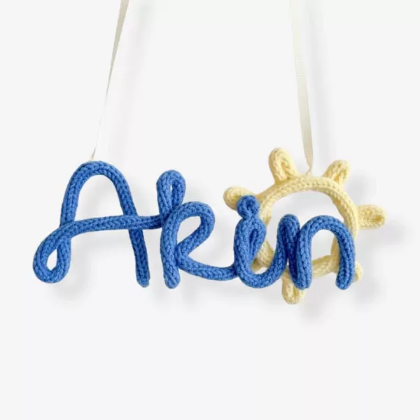 Knitted blue name 'Arin' with a yellow knitted sun hanging decor.