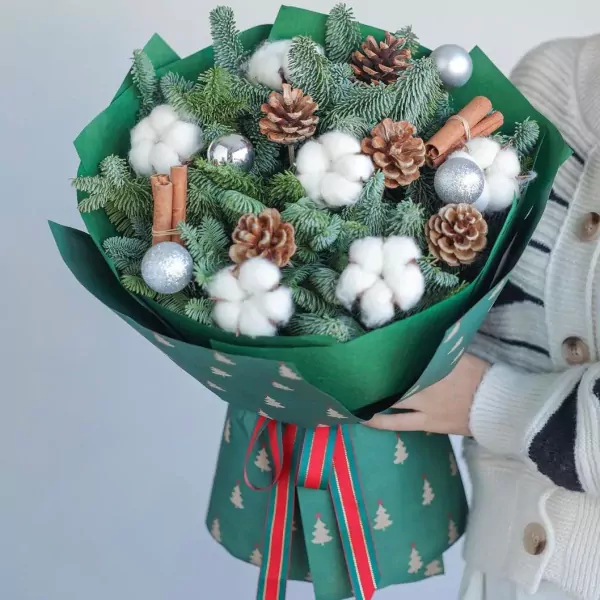 Christmas bouquet with pine, cotton, pine cones, cinnamon sticks, and silver ornaments.