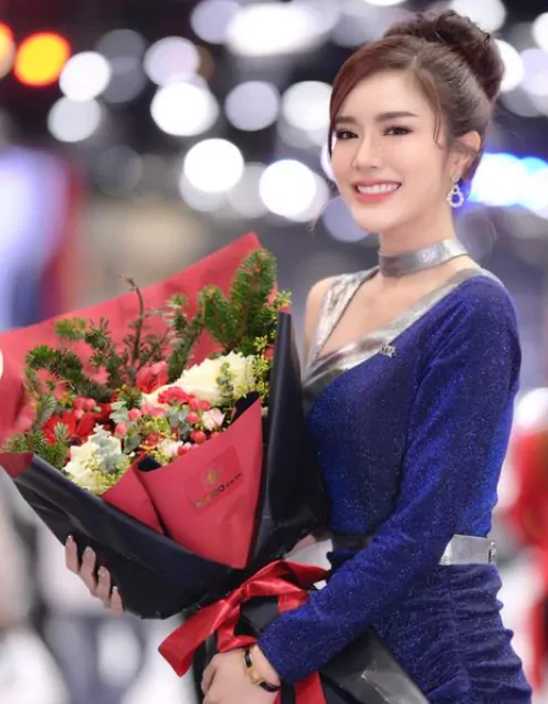 Woman in blue dress holding a bouquet of white roses, red flowers, and pine.