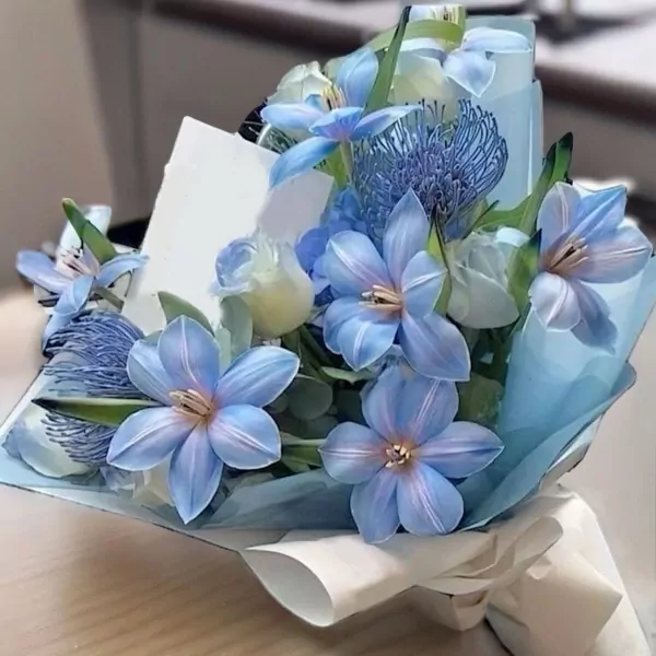 Bouquet of light blue and white flowers with delicate petals, wrapped in pale blue and white paper.