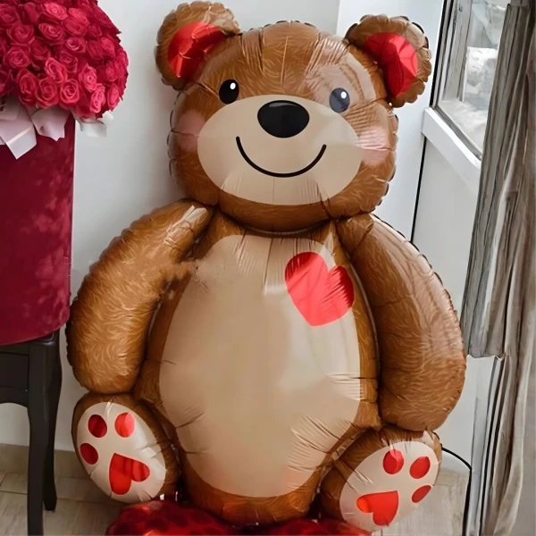 Giant brown teddy bear balloon with a red heart on its chest and red paw prints.