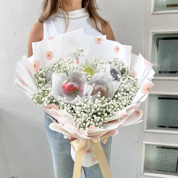 Fresh fruit bouquet in clear spheres with baby's breath and floral wrapping.