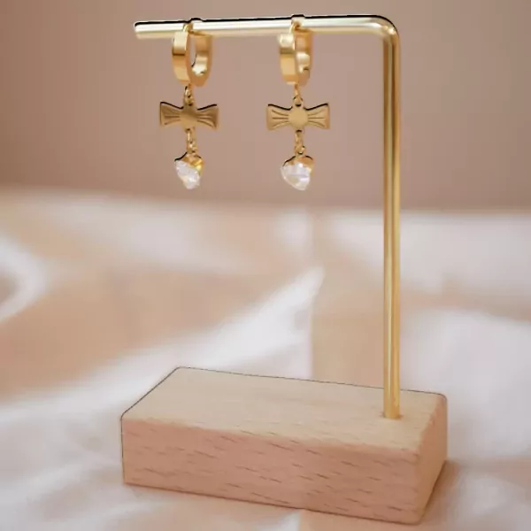 Gold cross earrings with crystal heart drops on a gold stand.