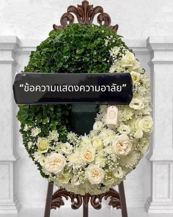 White floral wreath with a black ribbon displaying Thai text for condolences.