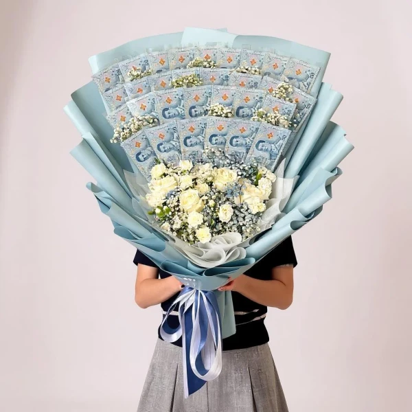 Money bouquet wrapped in blue paper with white flowers, held by a person.