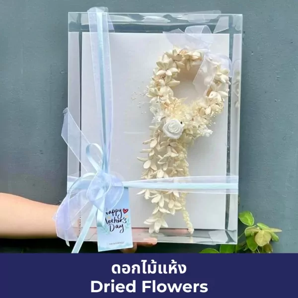 Clear gift box with dried floral garland, blue ribbon, and "Happy Mother's Day" tag.