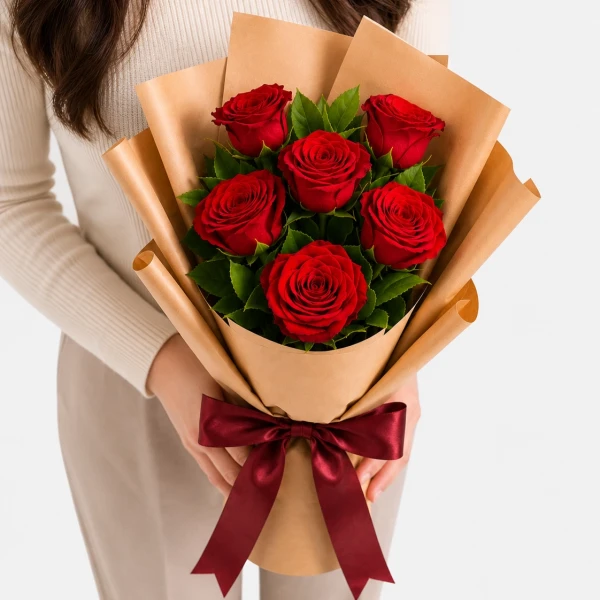 Six red roses in brown paper wrapping, tied with a red ribbon.