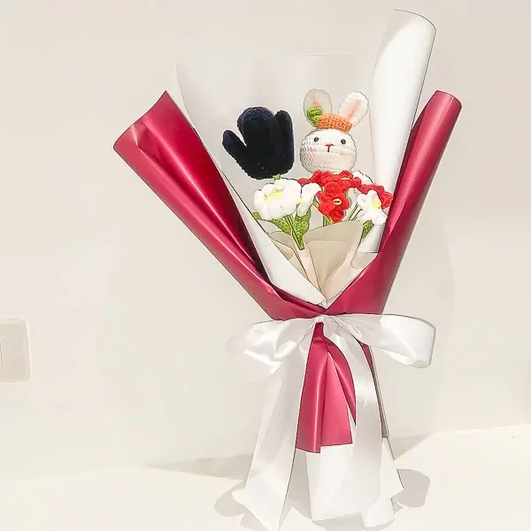 Crocheted bunny and flowers in a red and white bouquet, tied with a white ribbon.