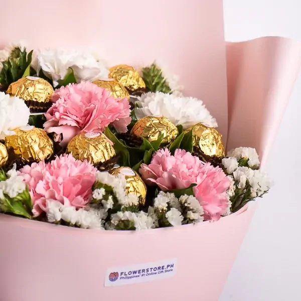 Pink and white carnations and white statice with Ferrero Rocher chocolates in pink wrapping.