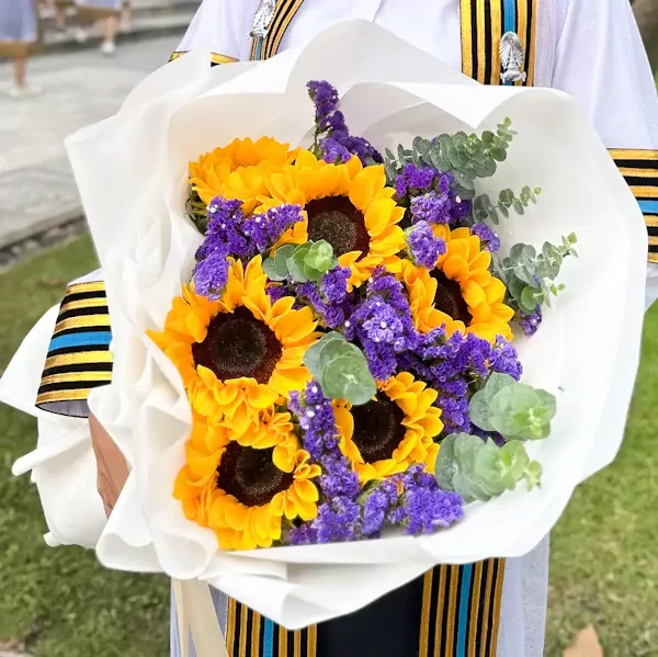 Bright sunflowers and purple statice flowers in a round bouquet.