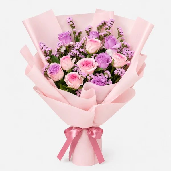 Pink and white roses with purple statice in pink paper with a pink ribbon.