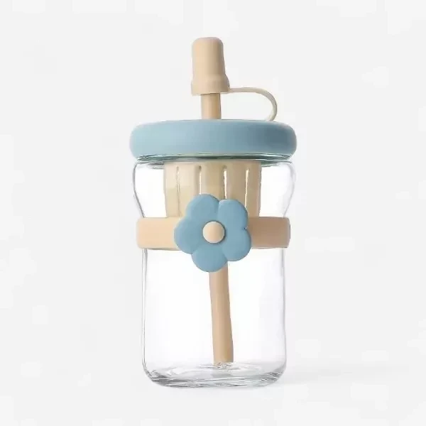 Clear glass water bottle with blue lid, beige flower accent, and straw.