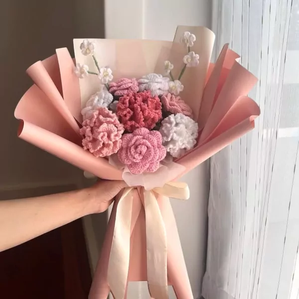 Crocheted bouquet of pink, white, and coral flowers with pink paper and ribbon.