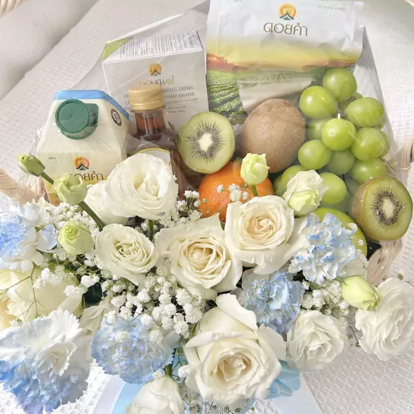 A fruit and flower basket with Doi Kham products and white roses.