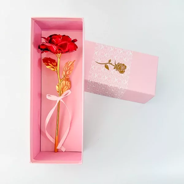 Red and gold artificial rose in a pink gift box with a bow.