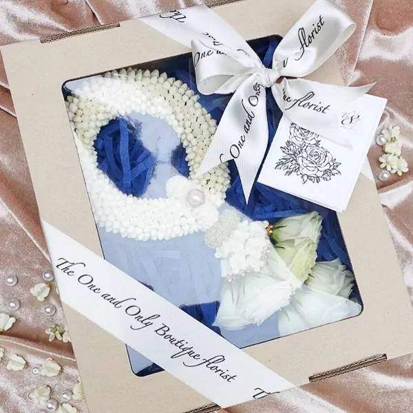 Jasmine garland in a gift box with white ribbon and roses.