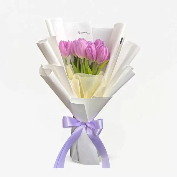 Purple tulips in white wrapping paper tied with a lavender ribbon.