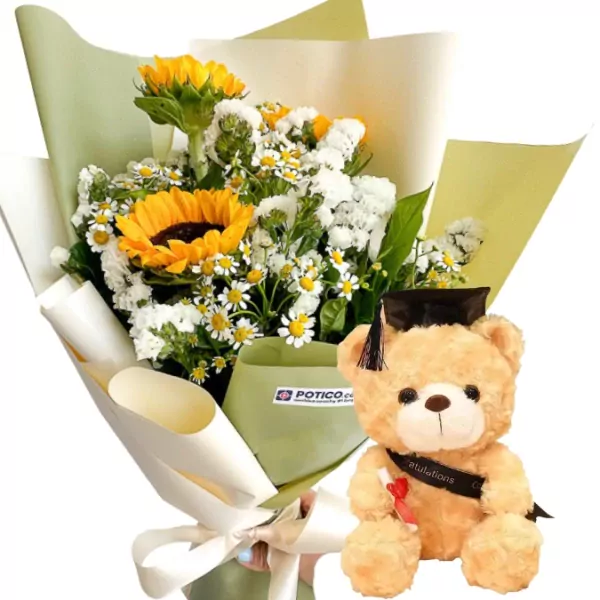 Graduation teddy bear with black cap and diploma beside a bouquet of sunflowers and daisies.