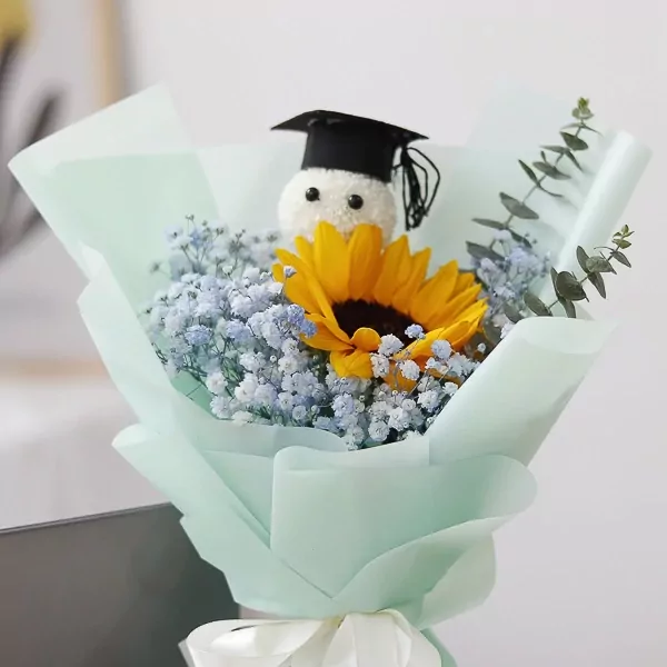 Graduation bouquet with a stuffed toy wearing a cap, sunflower, baby's breath, and eucalyptus.