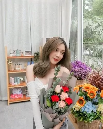 Woman holding a bouquet of pink roses and red carnations with eucalyptus.