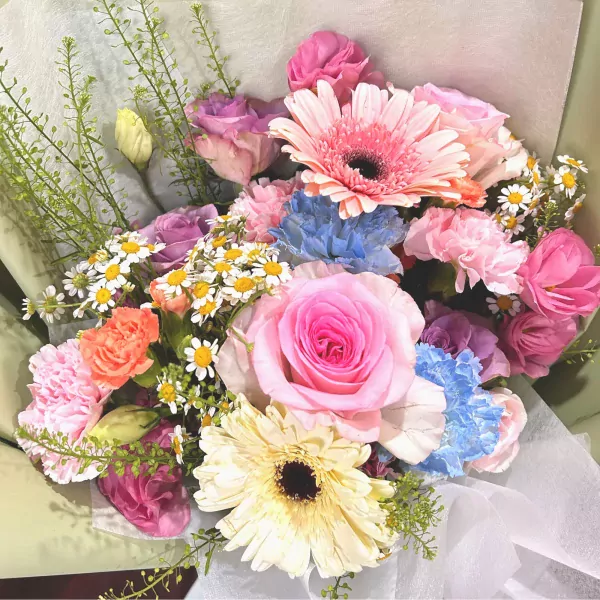 Pastel bouquet with pink roses, gerberas, blue carnations, and daisies.