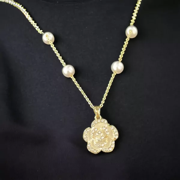 Gold chain necklace with pearl accents and a diamond-encrusted flower pendant.