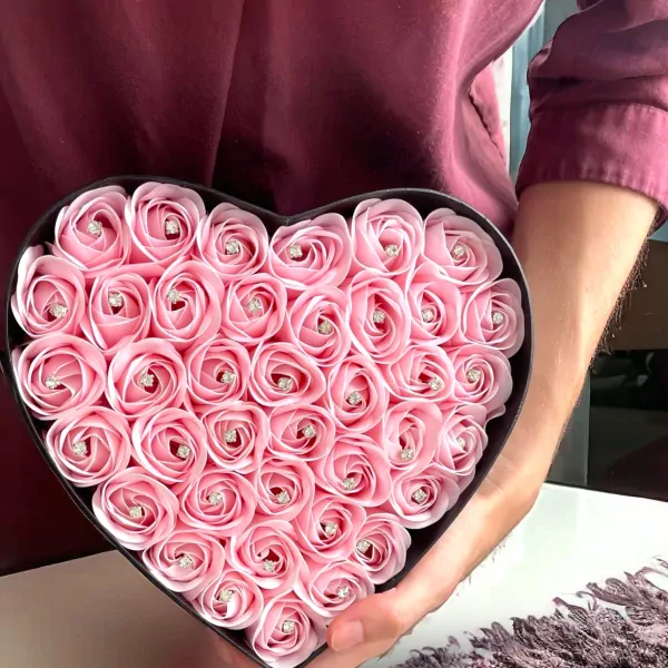 Heart-shaped box filled with pink roses, each with a small diamond accent.