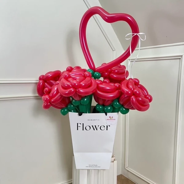 Red rose balloon arrangement in a white vase, topped with a heart balloon.
