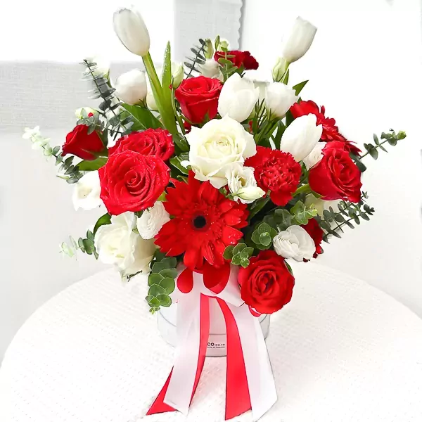 Red and white flowers in a box with red and white ribbons.