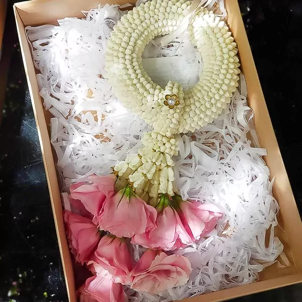 A white jasmine garland with pink roses in a gift box.