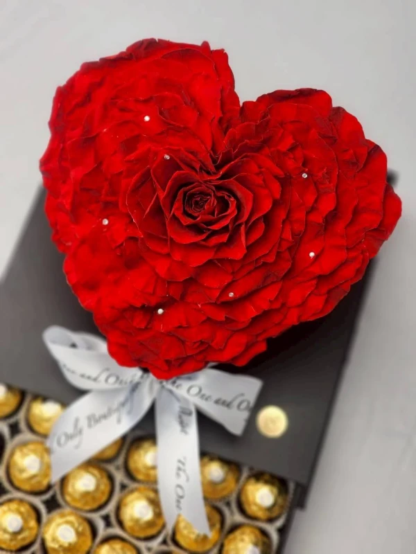 Heart-shaped red rose with rhinestones atop a box of Ferrero Rocher chocolates, tied with a ribbon.