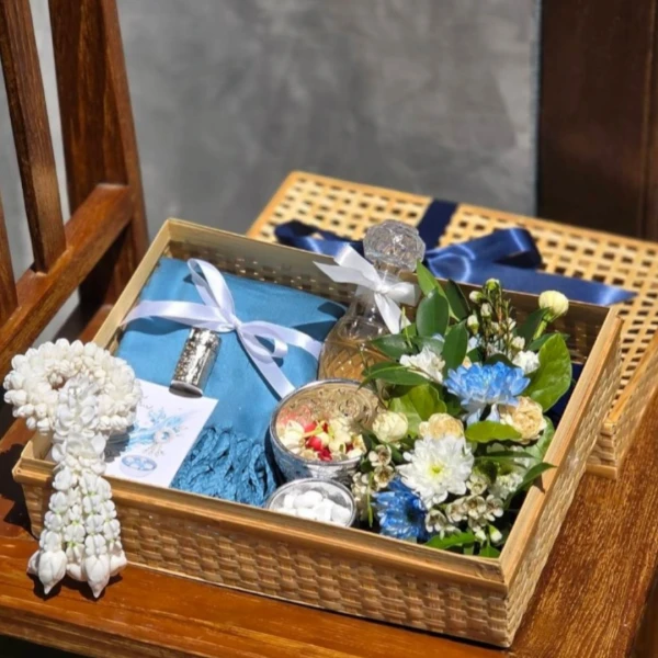A gift set for Songkran with a blue scarf, perfume, flowers, and a garland.