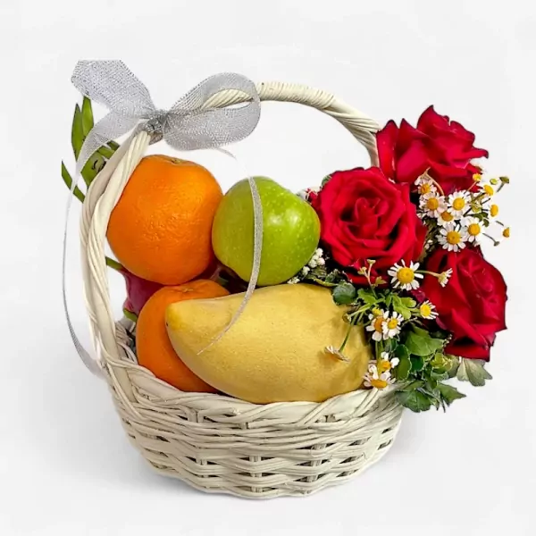 Fruit basket with oranges, mango, apples, red roses, and daisies, tied with a silver ribbon.