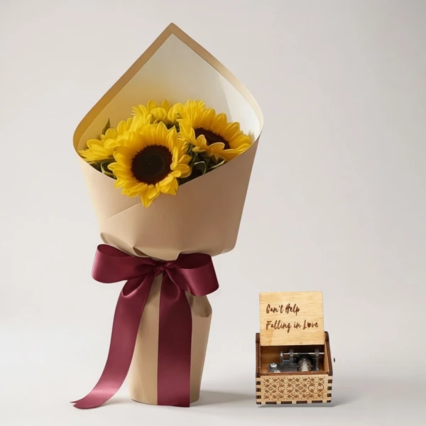 Sunflowers in a kraft paper bouquet with a burgundy ribbon next to a wooden music box playing "Can't Help Falling in Love."