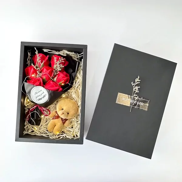 Gift box with red soap roses, teddy bear keychain, and fairy lights.