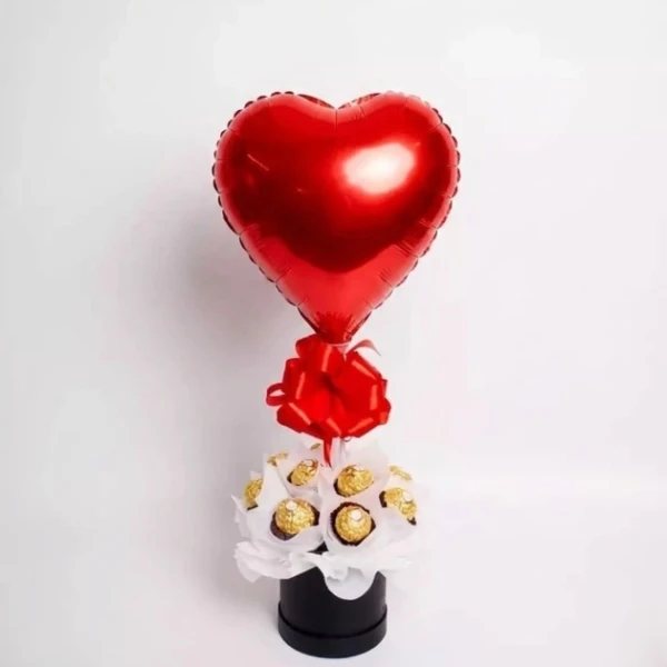 Red heart balloon and Ferrero Rocher chocolates in a black box with a red bow.
