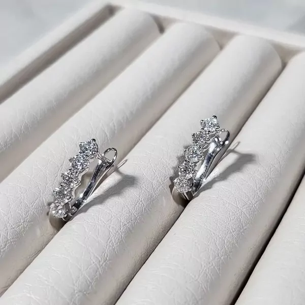 Sparkling 3MM moissanite diamond drop earrings with omega clip closure on white velvet display.