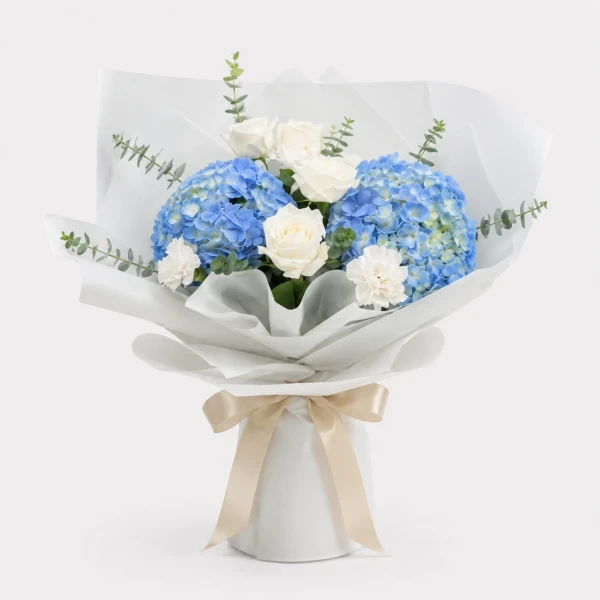 Bouquet of blue hydrangeas, white roses, white carnations, and eucalyptus, wrapped in white and blue paper.
