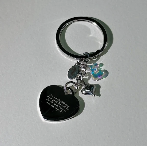 Silver heart-shaped keychain with engraved text and holographic initial charm.