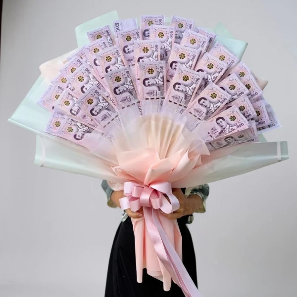 Bouquet of 500 Thai Baht banknotes arranged with pink and white paper, tied with a pink bow.