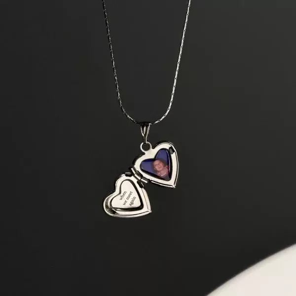 Silver heart-shaped locket necklace with a photo of a child and text that reads "when we meet again".