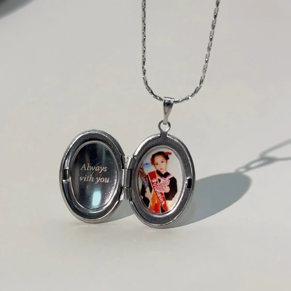 Silver oval locket necklace open, showing a child's photo and inscription "Always with you".