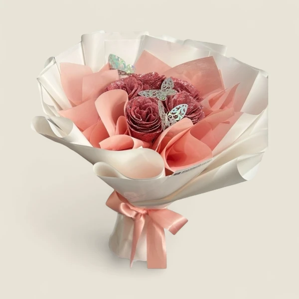 Bouquet of glittery pink roses wrapped in white and pink paper, adorned with silver butterflies and a pink ribbon.