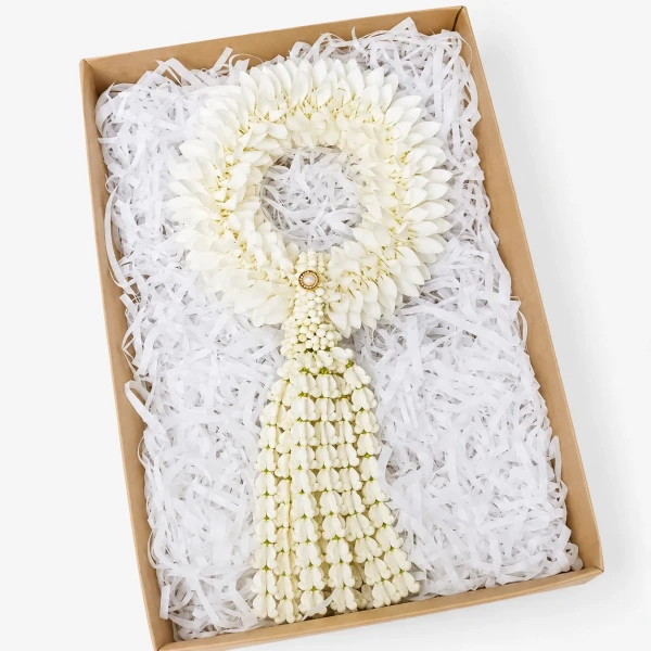 White flower garland with pearl accent in a gift box with white paper shredding.