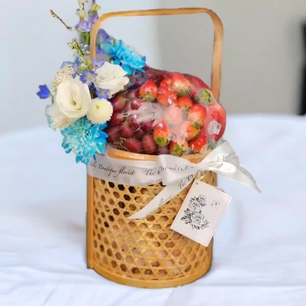 Woven basket with fruit and flowers, tied with a ribbon.