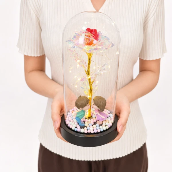 Glass dome with holographic rose, miniature couple, and LED lights, held by a person.